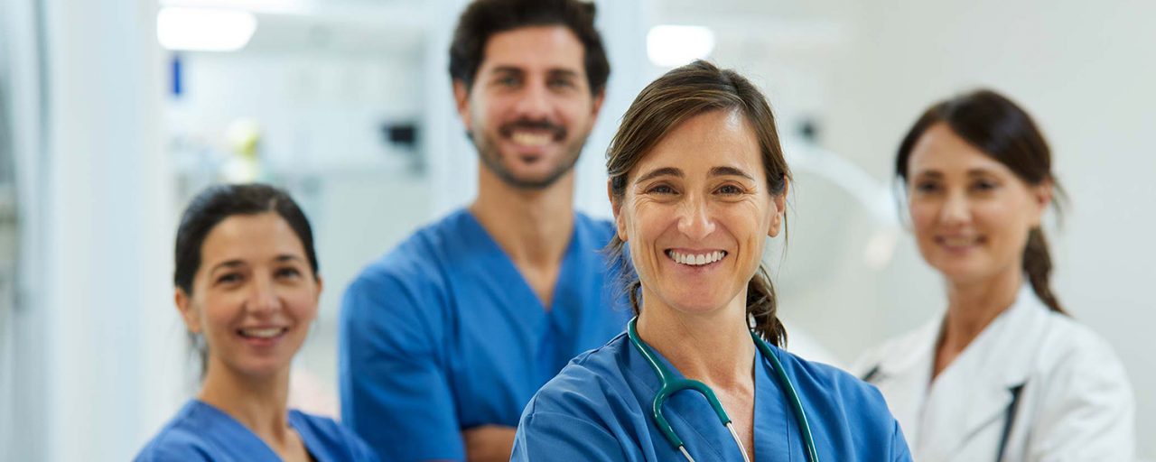 middle aged adult nurse stands with her team in the background