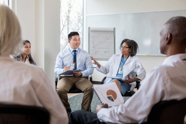 mature female doctor conducts a group conversation with colleagues