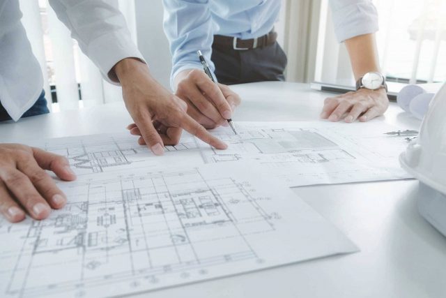 architects lean over desk to review floorplans